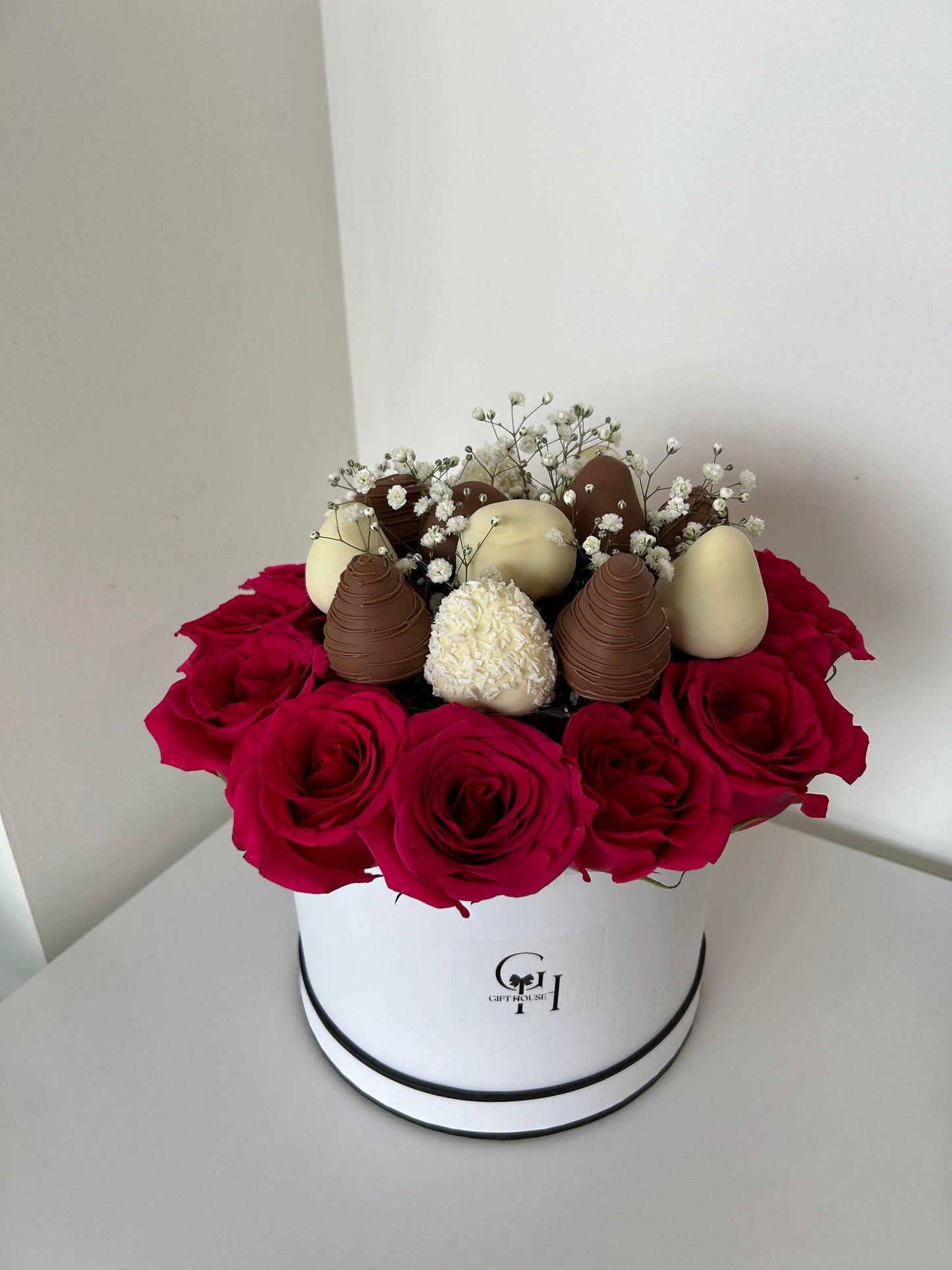 chocolate covered strawberries and red roses in white floral box on white background