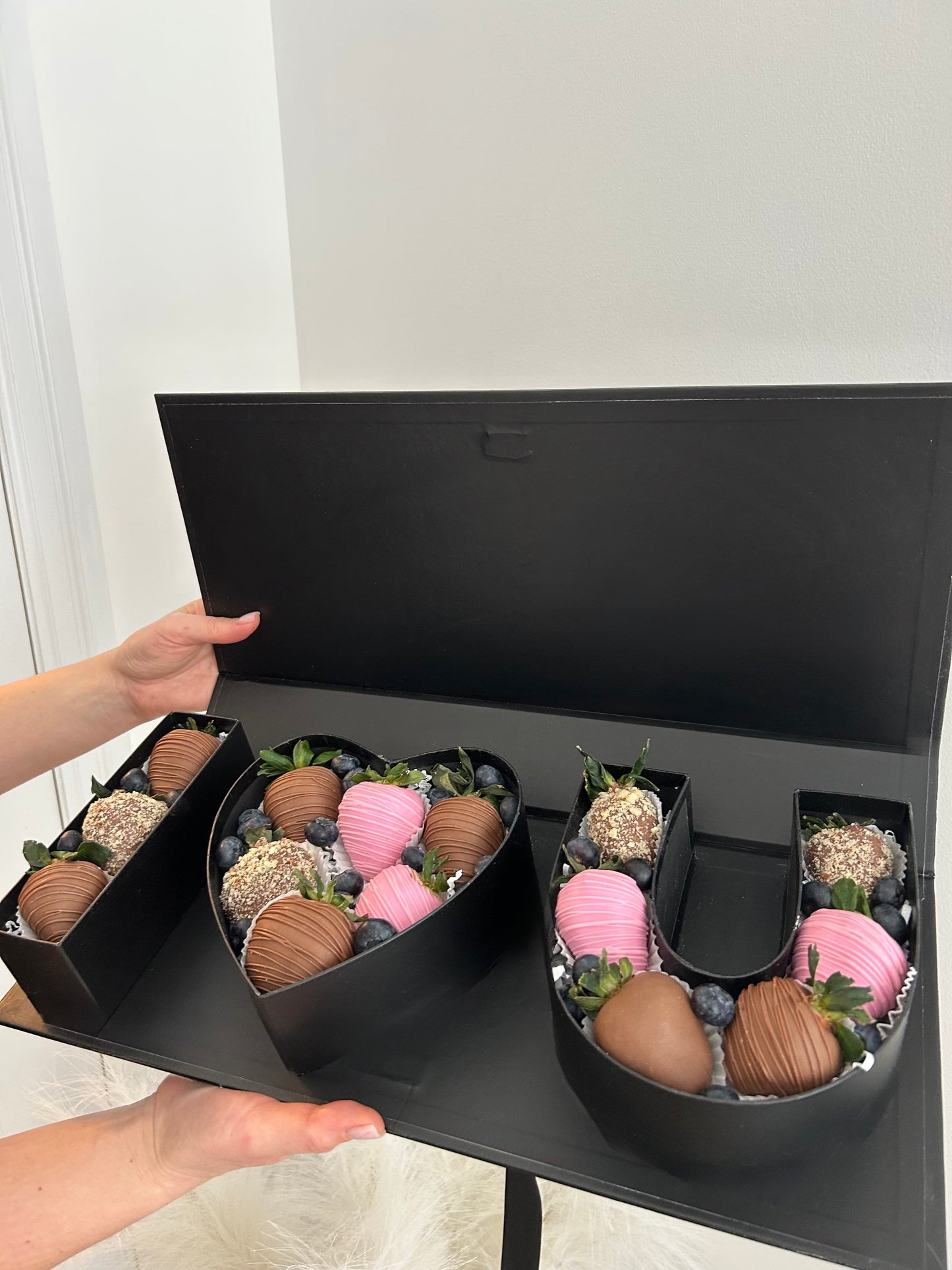 Black gift box with chocolate covered strawberries, on a white background